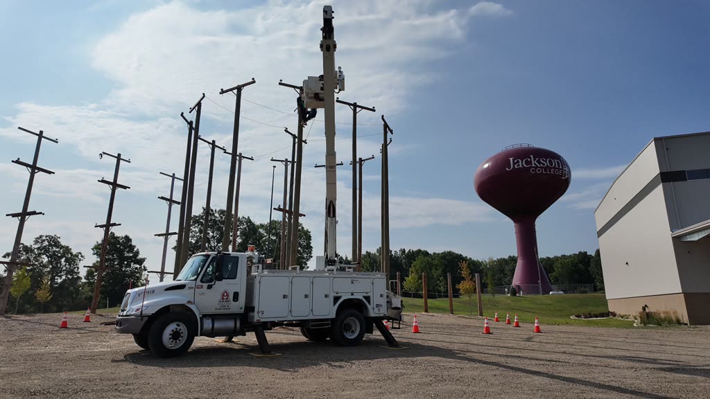 Bucket truck parked in the pole yard with a water tower behind