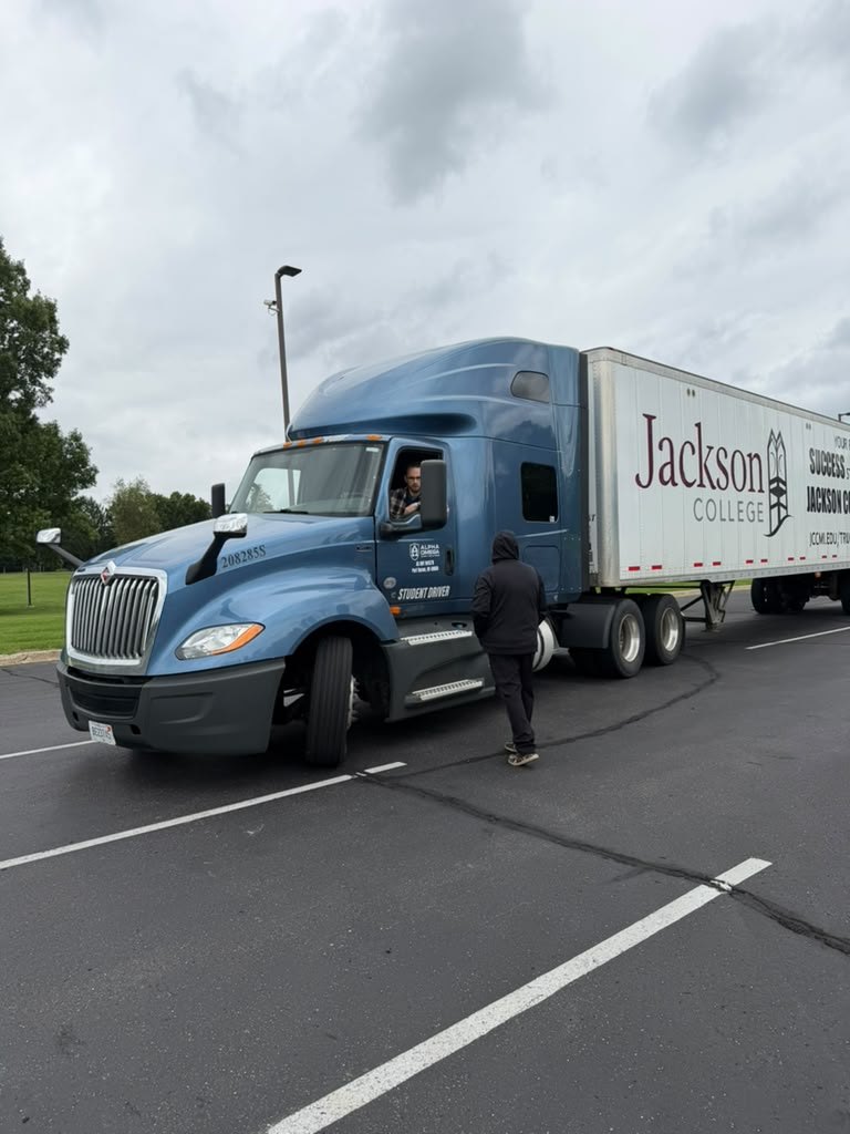 Blue Alpha Omega tractor pulling a Jackson College trailer on the road during behind-the-wheel training
