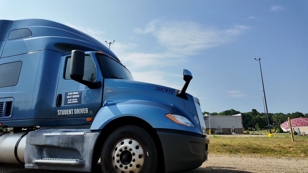 Blue Alpha Omega student-driver tractor parked in the training yard under a clear sky