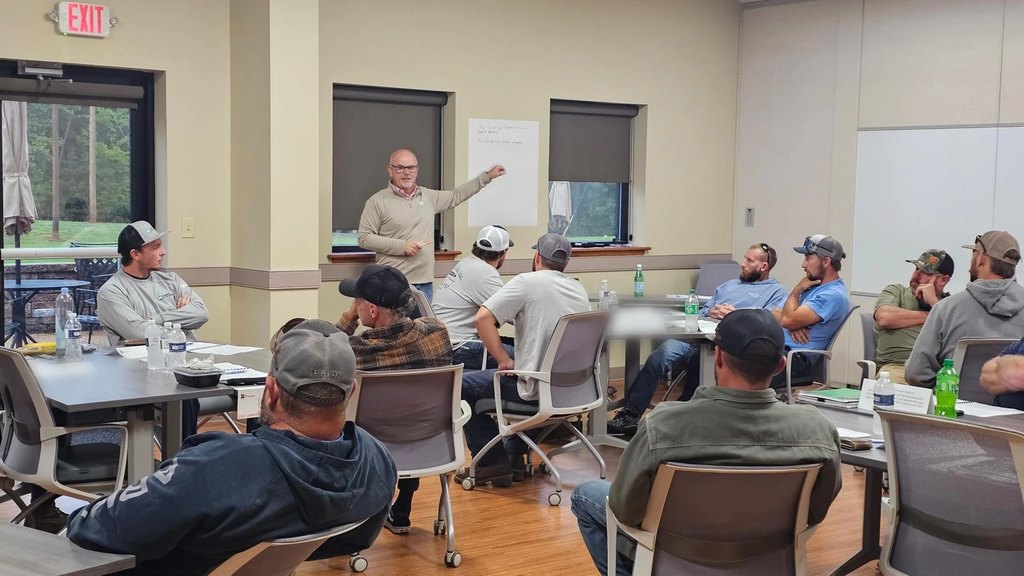 Alpha Omega COO Jeremy Adcock at a flip chart leading a safety session for a room of seated utility crew members