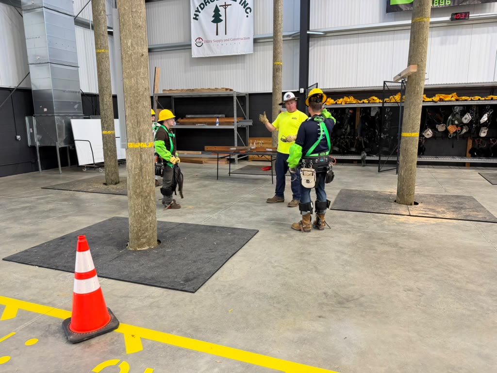 Two crew members in hi-vis vests working at the base of an indoor training pole