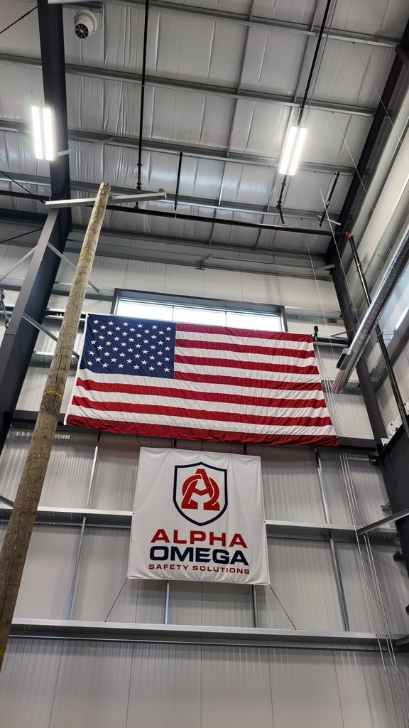 Alpha Omega Safety Solutions banner and a US flag hung high on the wall of the indoor pole-training facility
