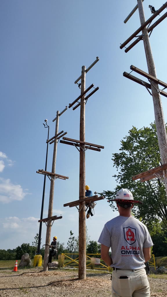An Alpha Omega instructor watching a trainee climb an outdoor utility pole