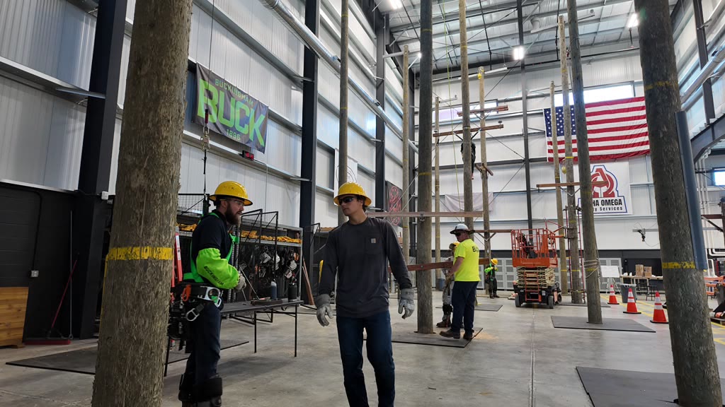 Wide view of the indoor pole-training facility with crews and equipment