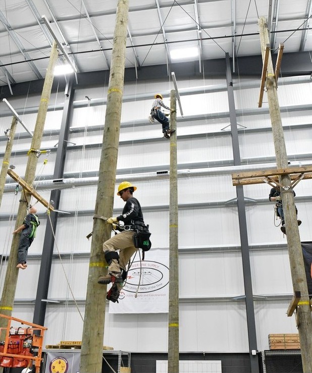 Trainees climbing wooden poles in the ATC indoor pole yard