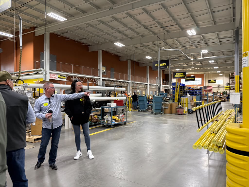 Alpha Omega instructor pointing out equipment during a safety walkthrough on a manufacturing floor