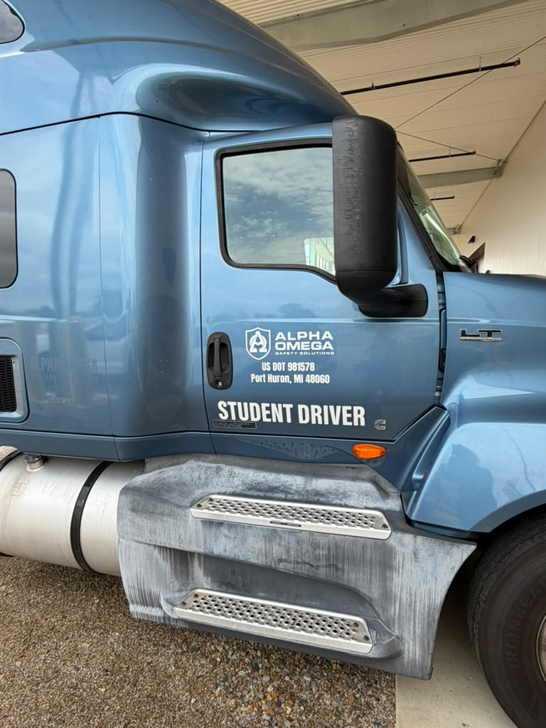 Alpha Omega Safety Solutions student-driver training semi with the AOSS shield and US DOT number on the cab door