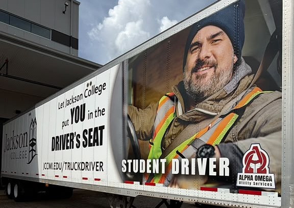 Jackson College “Let Jackson College put you in the driver’s seat” student-driver trailer wrap co-branded with Alpha Omega