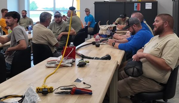 Electricians seated at the workbenches with primary cable, elbows and splicing tools laid out